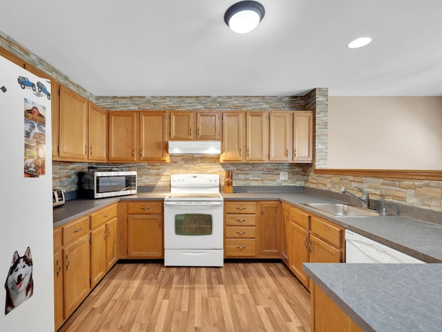 kitchen featuring a sink, light wood finished floors, tasteful backsplash, under cabinet range hood, and white appliances