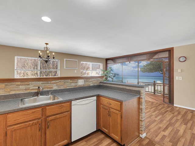 kitchen featuring a notable chandelier, a sink, white dishwasher, dark countertops, and light wood-style floors