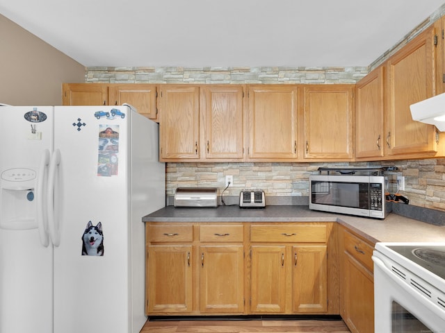kitchen featuring under cabinet range hood, tasteful backsplash, and white appliances