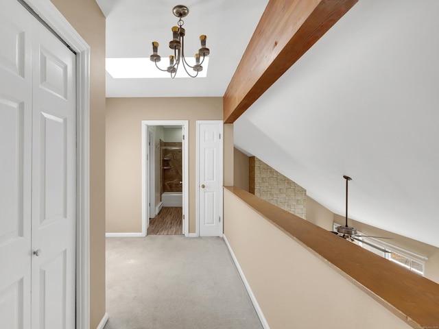 corridor with light colored carpet, vaulted ceiling with beams, baseboards, and a chandelier