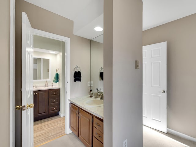 bathroom with a sink, two vanities, baseboards, and wood finished floors