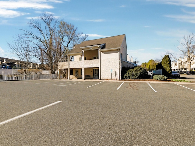 view of building exterior featuring uncovered parking and fence