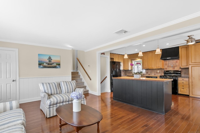 kitchen featuring dark wood-style floors, visible vents, black appliances, a kitchen island, and ornamental molding