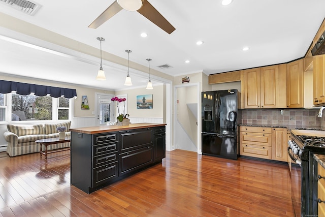 kitchen featuring butcher block countertops, tasteful backsplash, visible vents, and black appliances