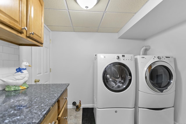 washroom featuring baseboards, washer and clothes dryer, and cabinet space