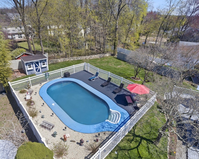 view of swimming pool featuring a deck, fence, an outbuilding, a yard, and a fenced in pool