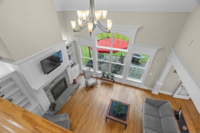 301 Fox Hopyard Rd, East Haddam, CT 06423 - living room featuring a glass covered fireplace, wood finished floors, a towering ceiling, a chandelier, and built in features