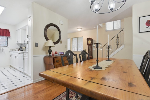 dining room with a wealth of natural light, stairs, light wood-style floors, and an inviting chandelier