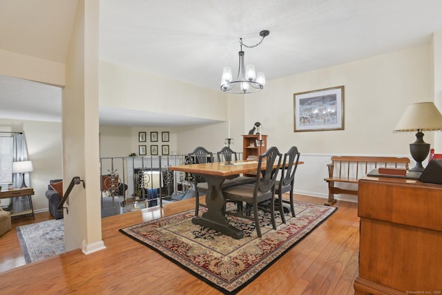 dining space with wood-type flooring, baseboards, and an inviting chandelier