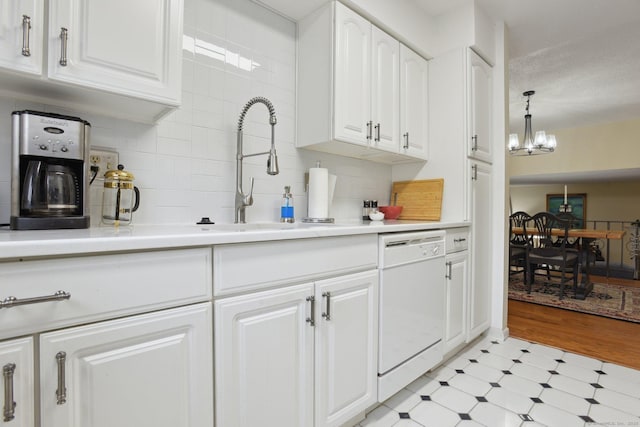 kitchen featuring light floors, white cabinets, a chandelier, a sink, and white dishwasher