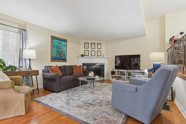 living room featuring a premium fireplace, wood finished floors, and baseboards