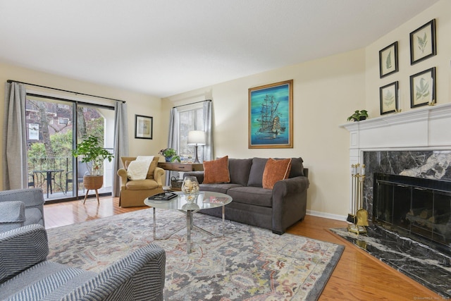 living area featuring wood finished floors, a high end fireplace, and baseboards