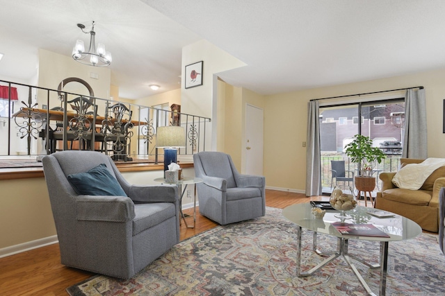 living room with baseboards, a chandelier, and wood finished floors