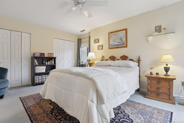 bedroom with baseboards, two closets, a ceiling fan, visible vents, and carpet
