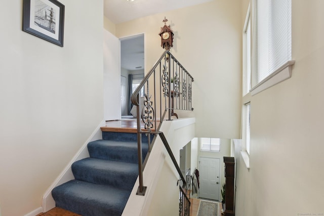 stairway featuring a high ceiling and baseboards