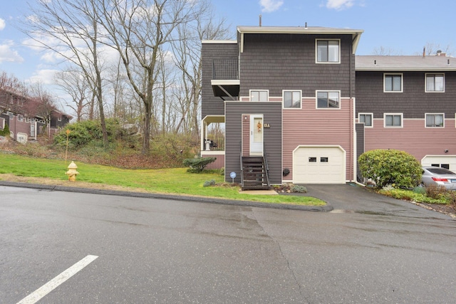 view of front facade with a garage, a front yard, and aphalt driveway