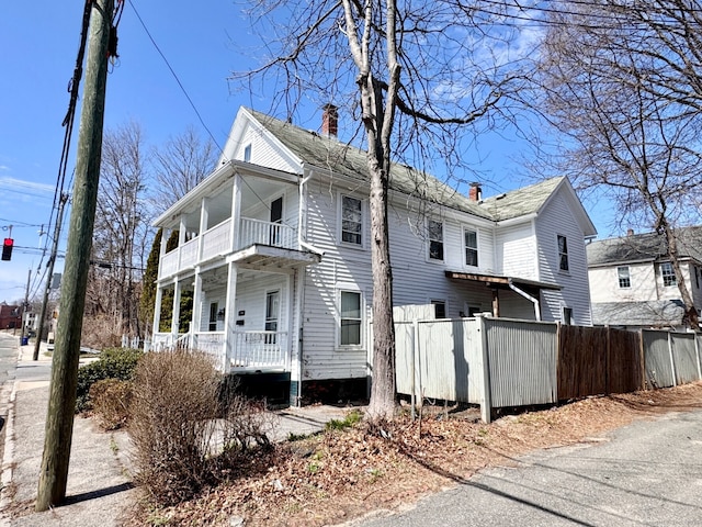 exterior space featuring a balcony, fence, a chimney, and a porch