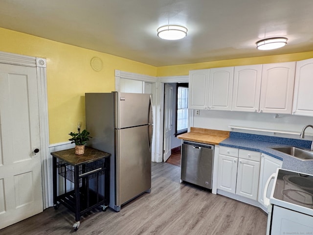 kitchen with appliances with stainless steel finishes, white cabinetry, light wood finished floors, and a sink