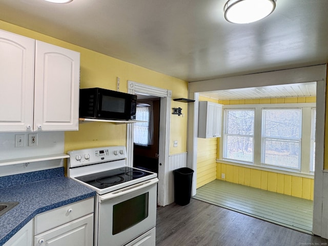 kitchen featuring black microwave, white electric range, plenty of natural light, and white cabinets