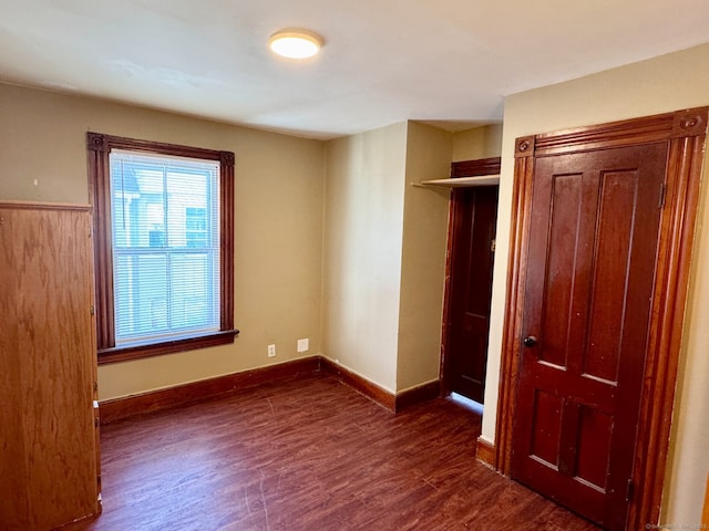 unfurnished bedroom featuring dark wood finished floors, baseboards, and a closet