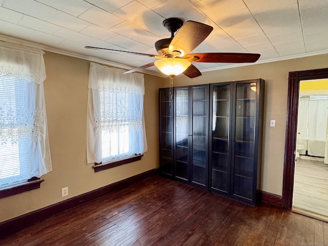 empty room featuring baseboards, a ceiling fan, wood finished floors, and crown molding