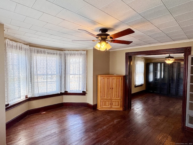 unfurnished room featuring baseboards, dark wood-style flooring, ceiling fan, and ornamental molding