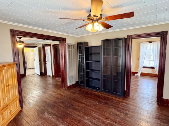 interior space with baseboards, crown molding, ceiling fan, and dark wood-type flooring