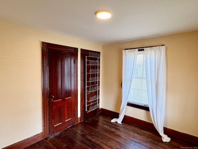 unfurnished bedroom with baseboards and dark wood-type flooring