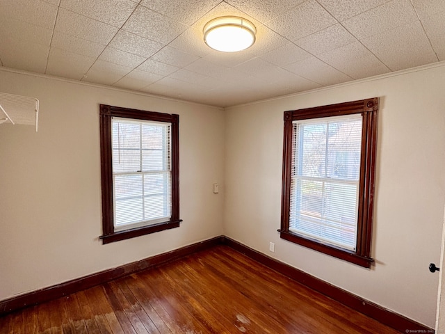 unfurnished room with dark wood-style floors, baseboards, and crown molding