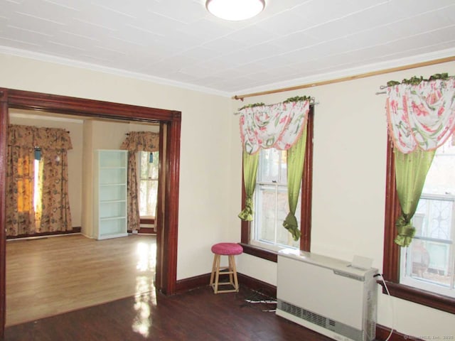 unfurnished room featuring baseboards, wood finished floors, and crown molding
