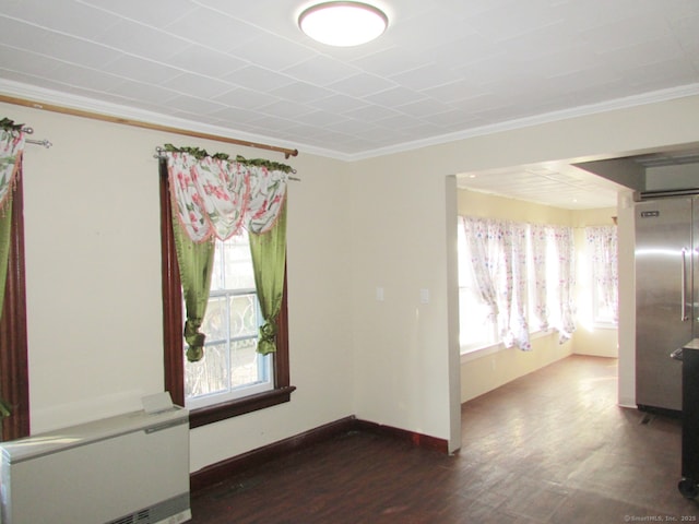 spare room featuring baseboards, wood finished floors, a healthy amount of sunlight, and crown molding