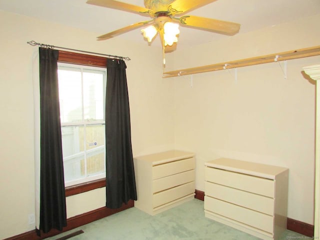 walk in closet with a ceiling fan and light carpet