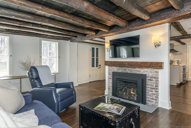 living area with dark wood-style floors, wood ceiling, beamed ceiling, and a brick fireplace