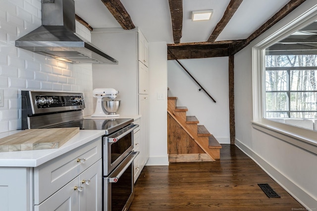 kitchen featuring visible vents, wall chimney range hood, dark wood-style floors, beam ceiling, and double oven range