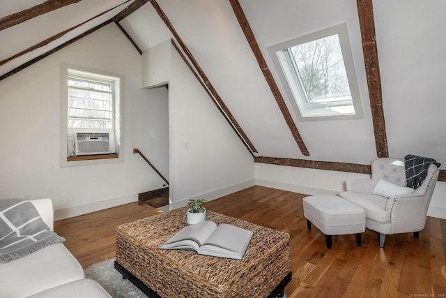 living room featuring cooling unit, vaulted ceiling with skylight, wood finished floors, and baseboards