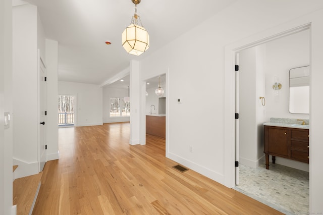 unfurnished dining area with visible vents, a sink, baseboards, and light wood-type flooring
