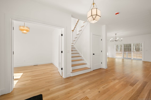 stairs featuring baseboards, wood finished floors, and a notable chandelier