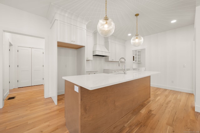kitchen with baseboards, a sink, white cabinetry, and custom exhaust hood