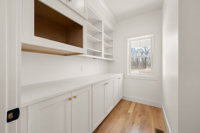 bar featuring baseboards, light wood-style flooring, and visible vents