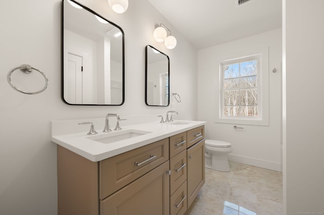bathroom with a sink, baseboards, toilet, and double vanity