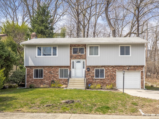 bi-level home with a chimney, a front lawn, driveway, a garage, and brick siding