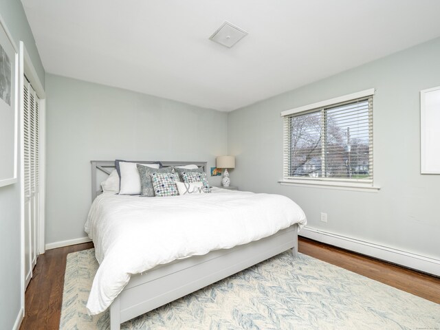 bedroom featuring baseboards, wood finished floors, and baseboard heating