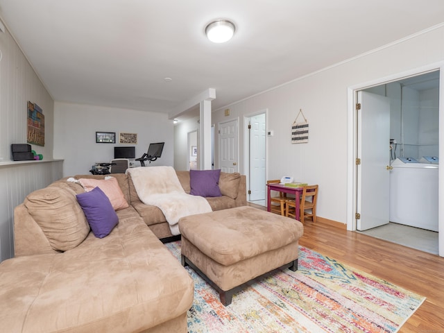 living area with crown molding, wood finished floors, and independent washer and dryer