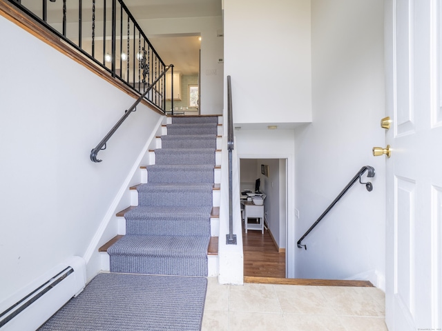stairs featuring a baseboard heating unit and tile patterned floors