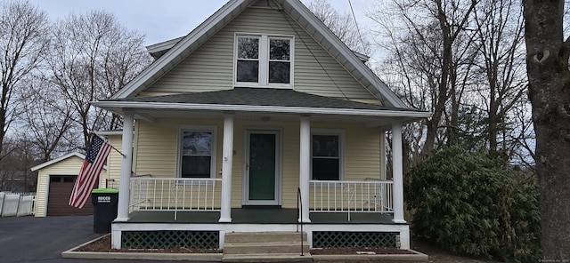 view of front of house with an outdoor structure, a porch, and roof with shingles