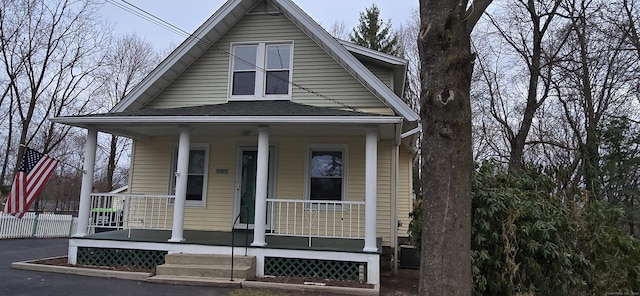 view of front of home with fence, a shingled roof, and a porch