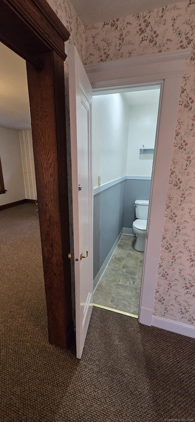 bathroom with baseboards, wallpapered walls, and toilet