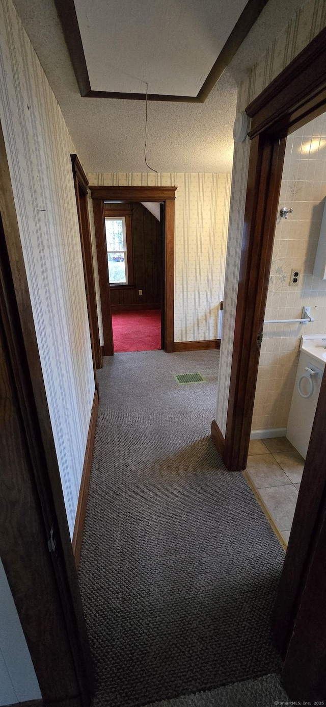 corridor with baseboards, wallpapered walls, visible vents, and carpet floors