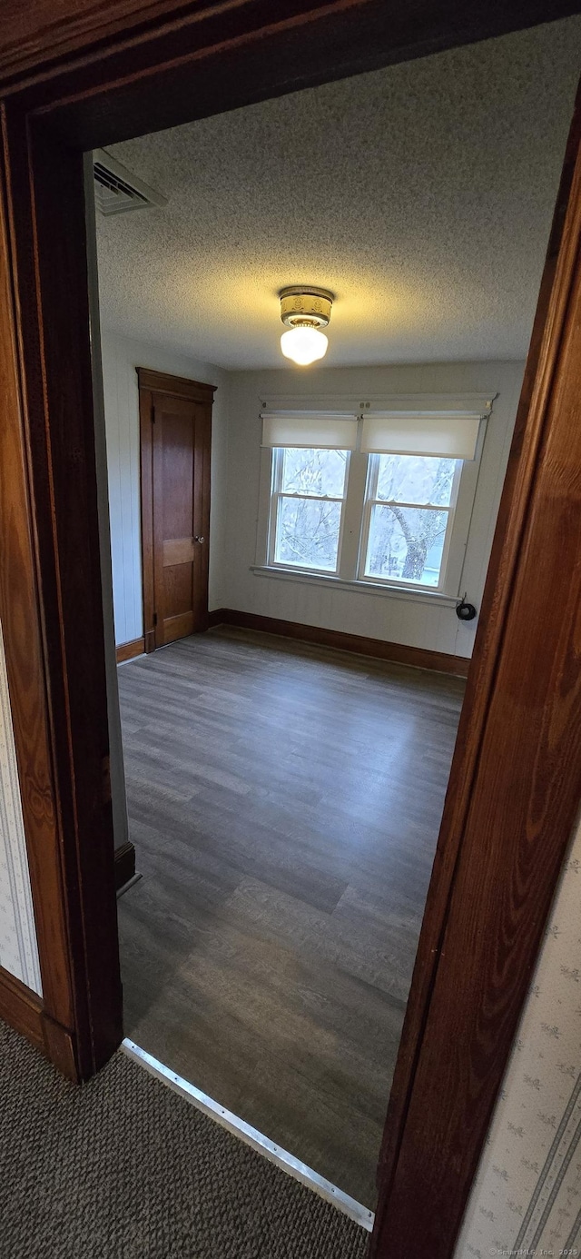 interior space with light wood-style flooring, visible vents, baseboards, and a textured ceiling