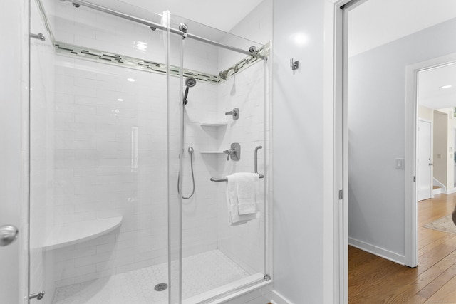 bathroom featuring a shower stall, wood finished floors, and baseboards